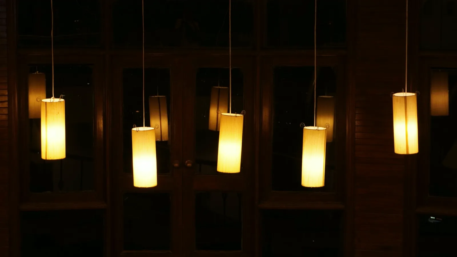 Five cylindrical pendant lights glowing in a dark interior
