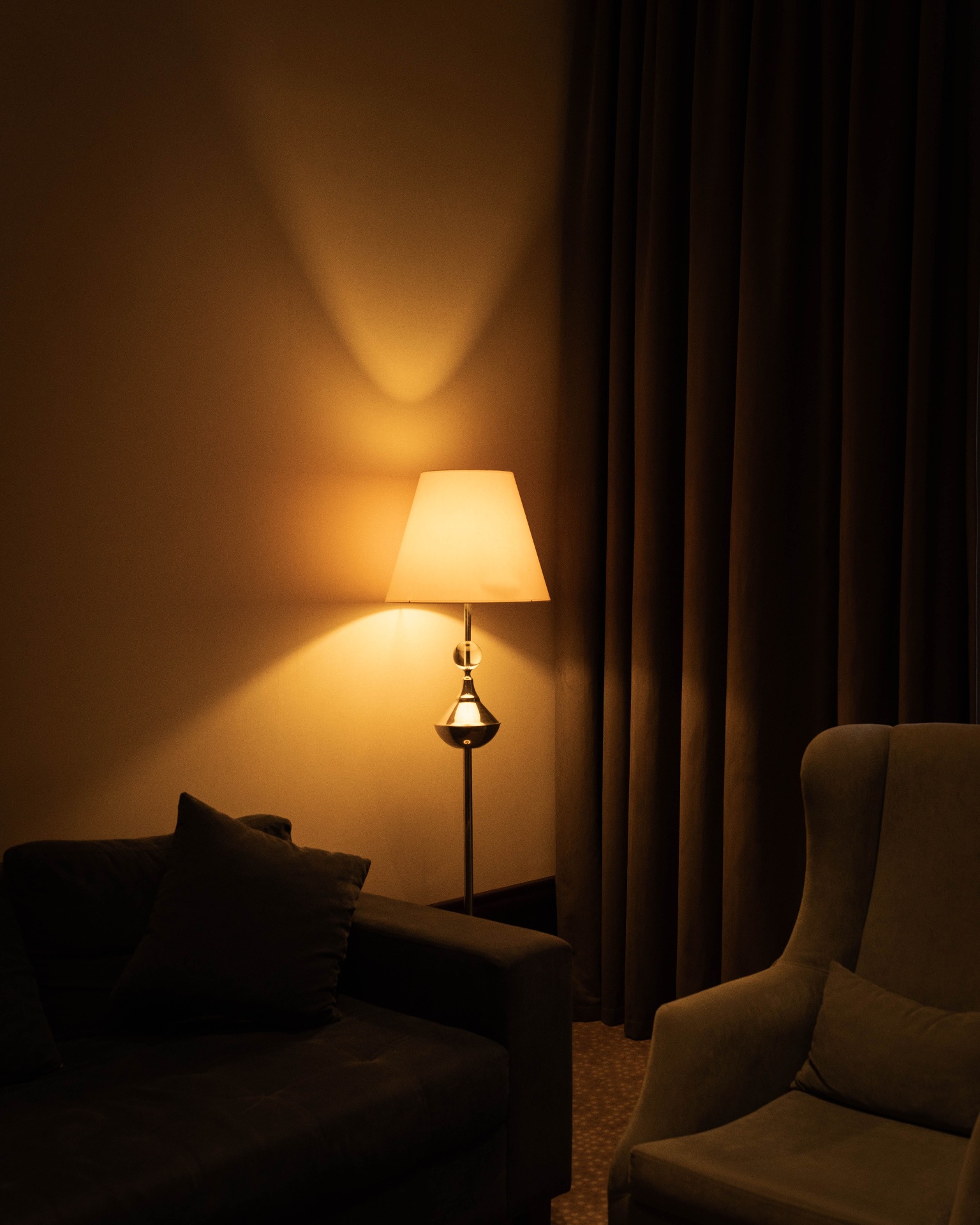 Warm floor lamp glowing against velvet curtains in a softly lit Singapore living room